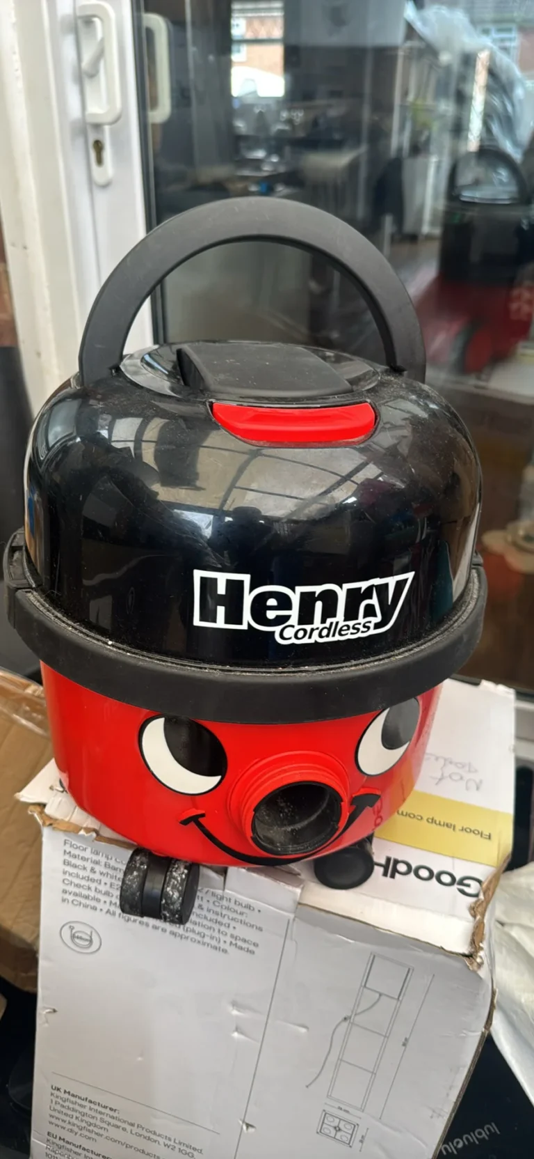 Black and red plastic vacuum cleaner with smiling face design, red handle