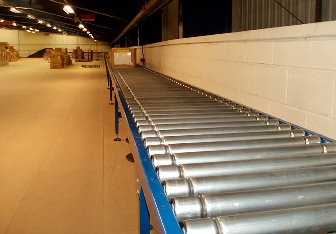 metal conveyor belt with cylindrical rollers and blue frame in warehouse storage