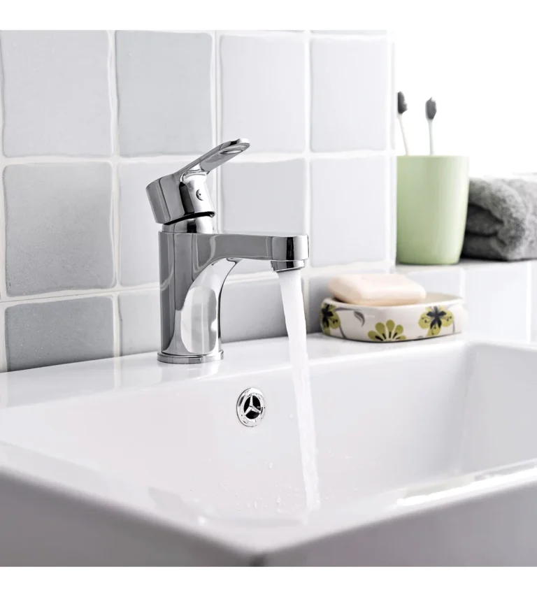 Chrome metal faucet with lever handle and water flowing into white sink,