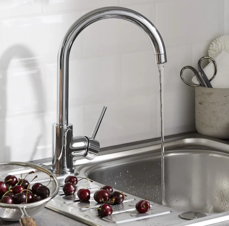 Chrome metal kitchen faucet with curved spout and lever handle, water flowing