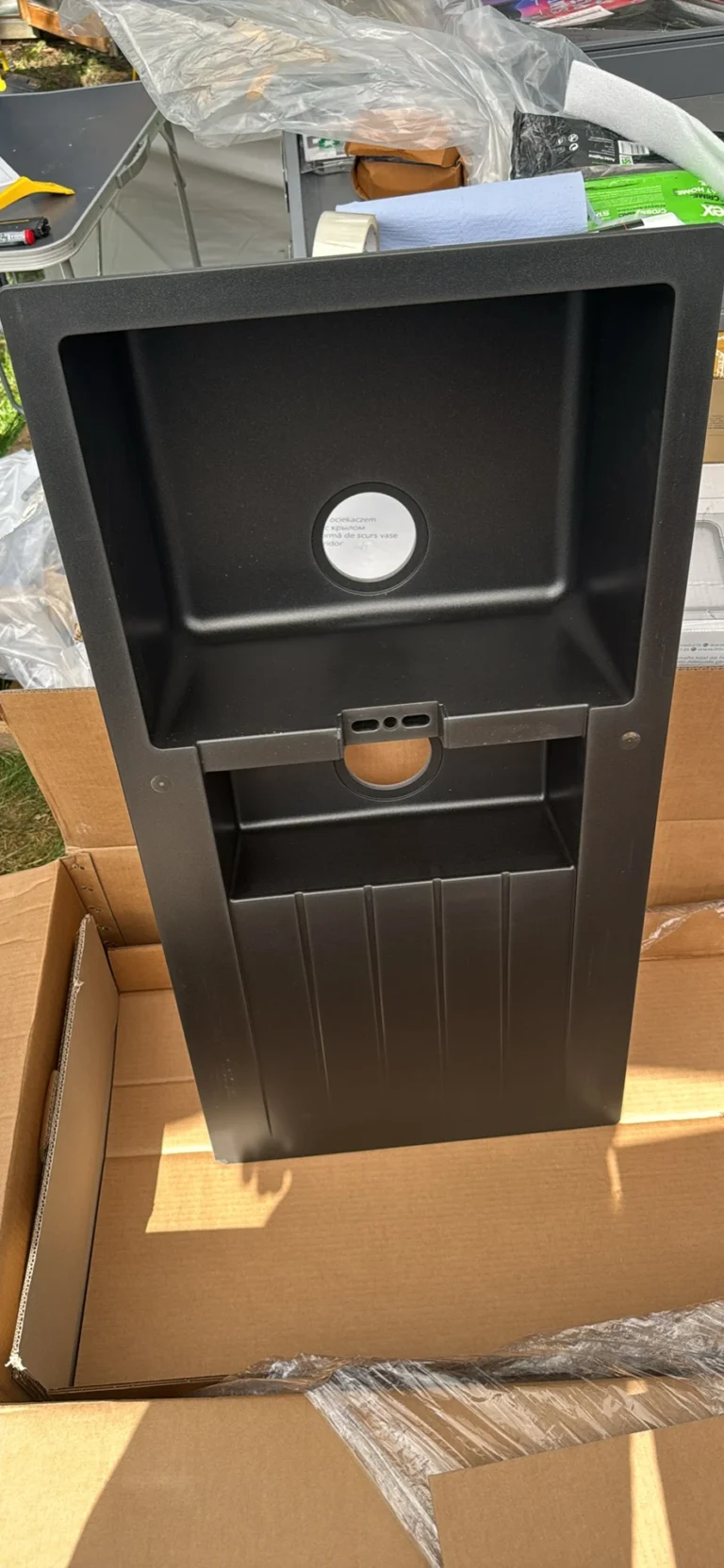 Black plastic rectangular container or panel with recessed area, circular hole